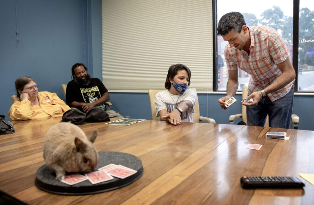 Magician Stephen Silva entertains potential recruit William McGlaughlin (and his dad Dan, left corner) with a card trick at a special Society of American Magicians meeting in Salem. (Robin Lubbock/WBUR)