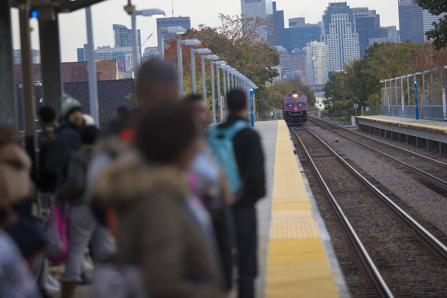 A group of students on their way to Jeremiah Burke High School wait as the Fairmount Line Commuter Rail train pulls into Uphams Corner Station in early morning. (Jesse Costa/WBUR)