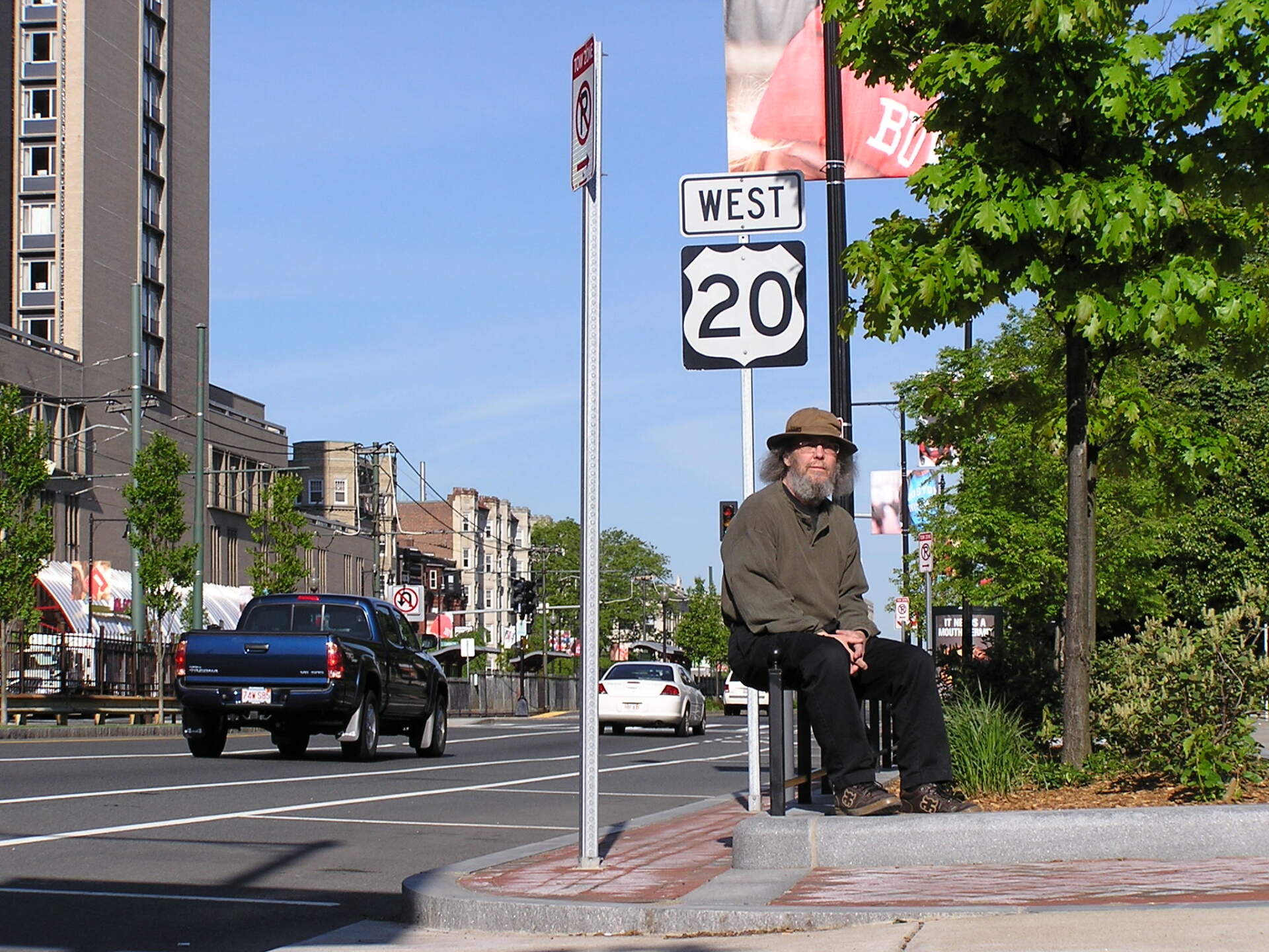 Michael Czarnecki sits beneath a sign for Route 20 west in Boston. (Courtesy Michael Czarnecki)
