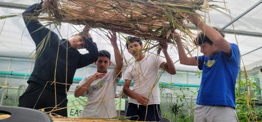 Climate Corps youth building marsh grass mats for coastal resilience in East Boston, with partner Emerald Tutu. Photo by Jenny Wechter, Eastie Farm