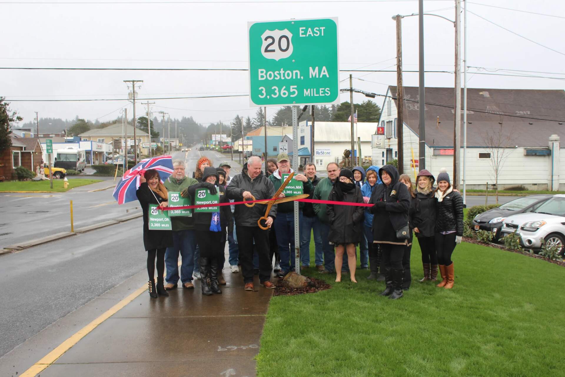 Officials and residents of Newport, Oregon at the 2016 ribbon cutting for a sign marking Boston's distance at the other end of U.S. Route 20, the country's longest road. (Photo courtesy the Oregon Coast Daily News)