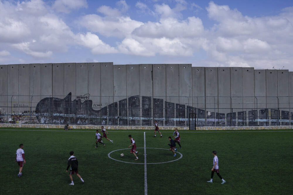 Palestinian youth play soccer in a field next to Israel's separation barrier in Aida Refugee camp, in the West Bank city of Bethlehem, Wednesday, March 8, 2023. (Mahmoud Illean/AP)