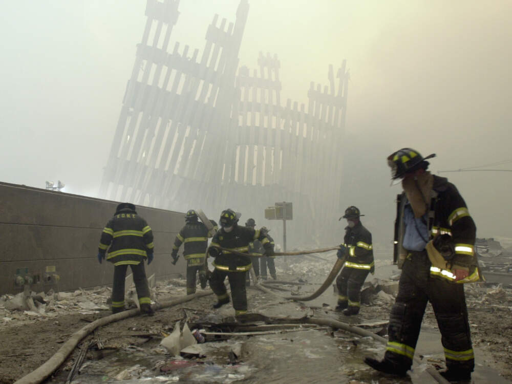 Firefighters work beneath the destroyed mullions, the vertical struts which once faced the soaring outer walls of the World Trade Center towers, after a terrorist attack in New York, Sept. 11, 2001. (Mark Lennihan/AP)