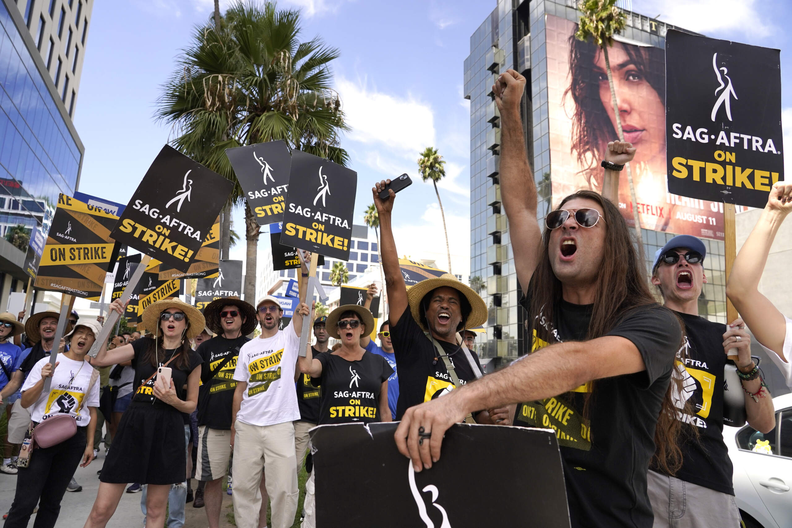 SAG-AFTRA member John Schmitt, second from right, and others carry signs on the picket line outside Netflix. Hollywood's writers strike was declared over Tuesday night when board members from their union approved a contract agreement with studios, bringing the industry at least partly back from a historic halt in production. The actors strike continues in their bid to get better pay and working conditions. (Chris Pizzello/AP)