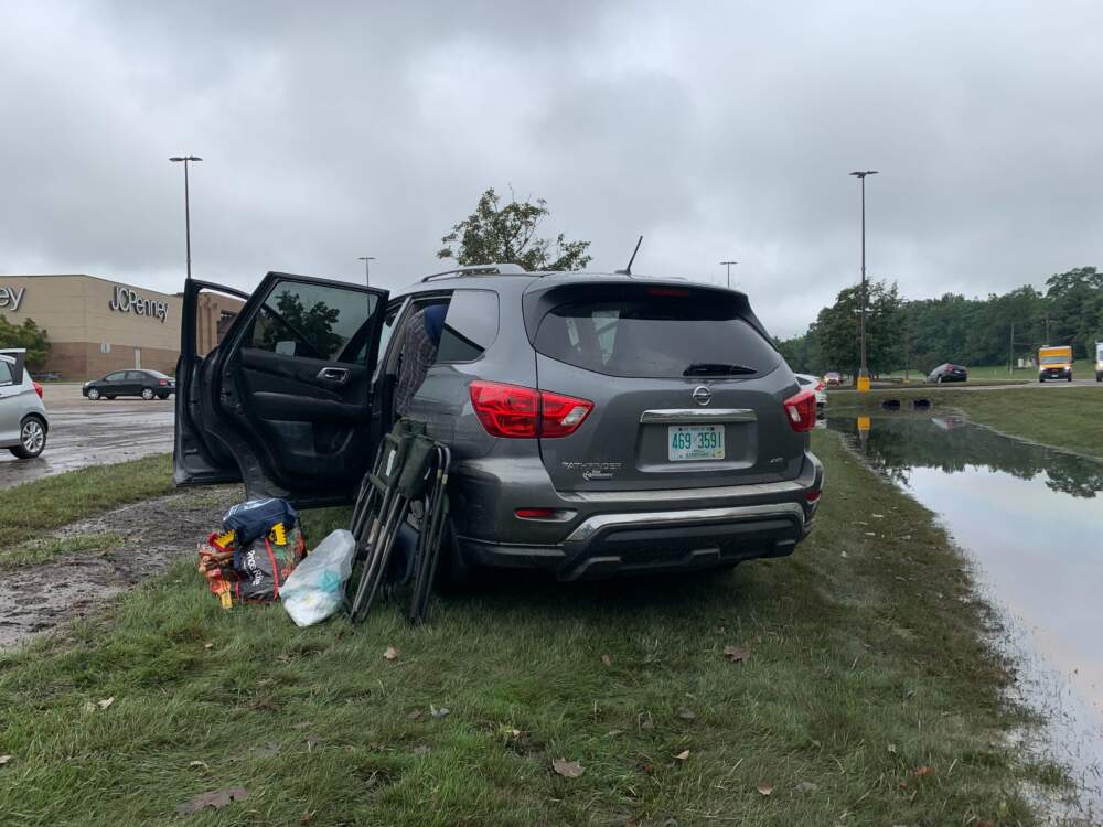 Joseph Lafrennie works to collect his belongings from his car that was washed into a ditch during the flooding in Leominster on Monday night. (Carrie Jung/WBUR)