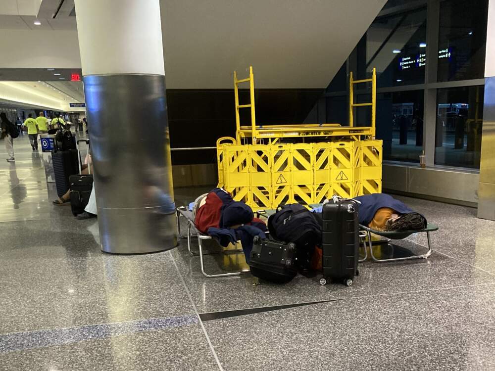 Some new arrivals find a spot under the escalators at Logan. (Gabrielle Emanuel/WBUR)