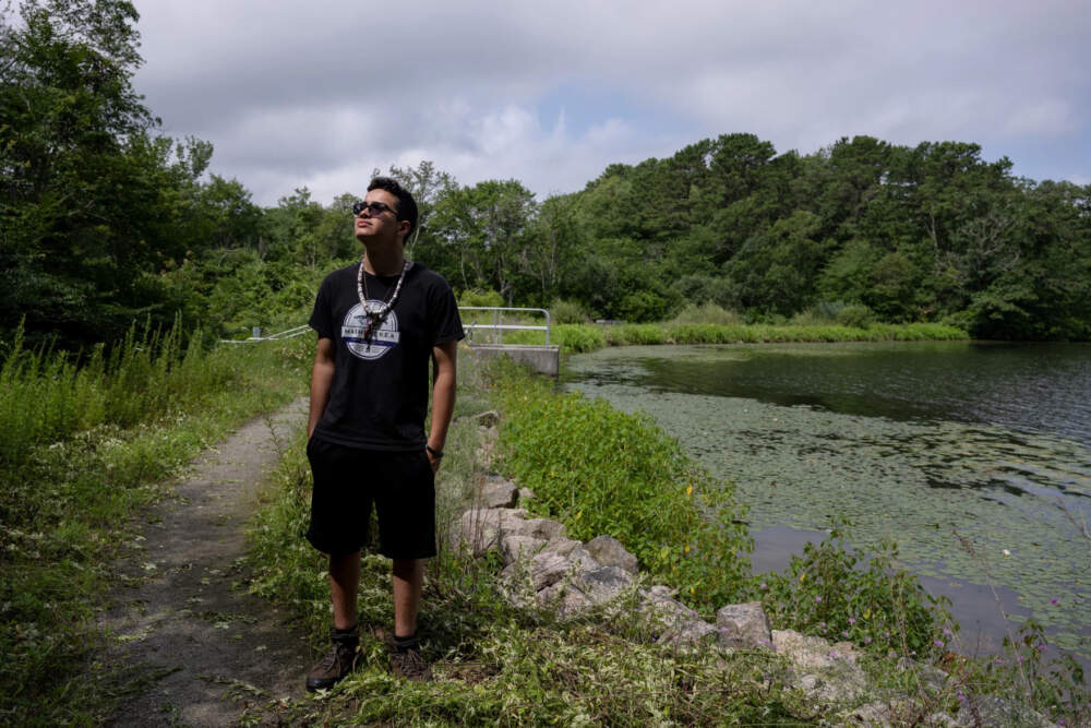Mashpee Wampanoag Tribe member Isaiah Peters looks out while standing along the edge of Santuit Pond