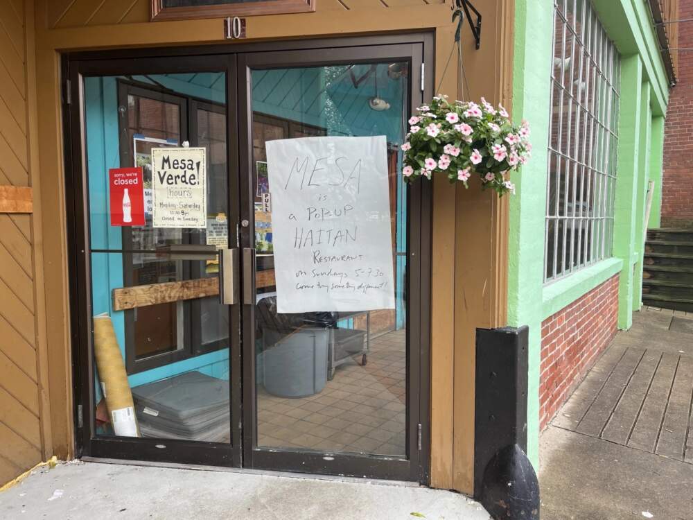 A sign posted on the front doors of Mesa Verde restaurant informs customers of the Haitian food pop-up Sunday nights. (Nirvani Williams/NEPM)