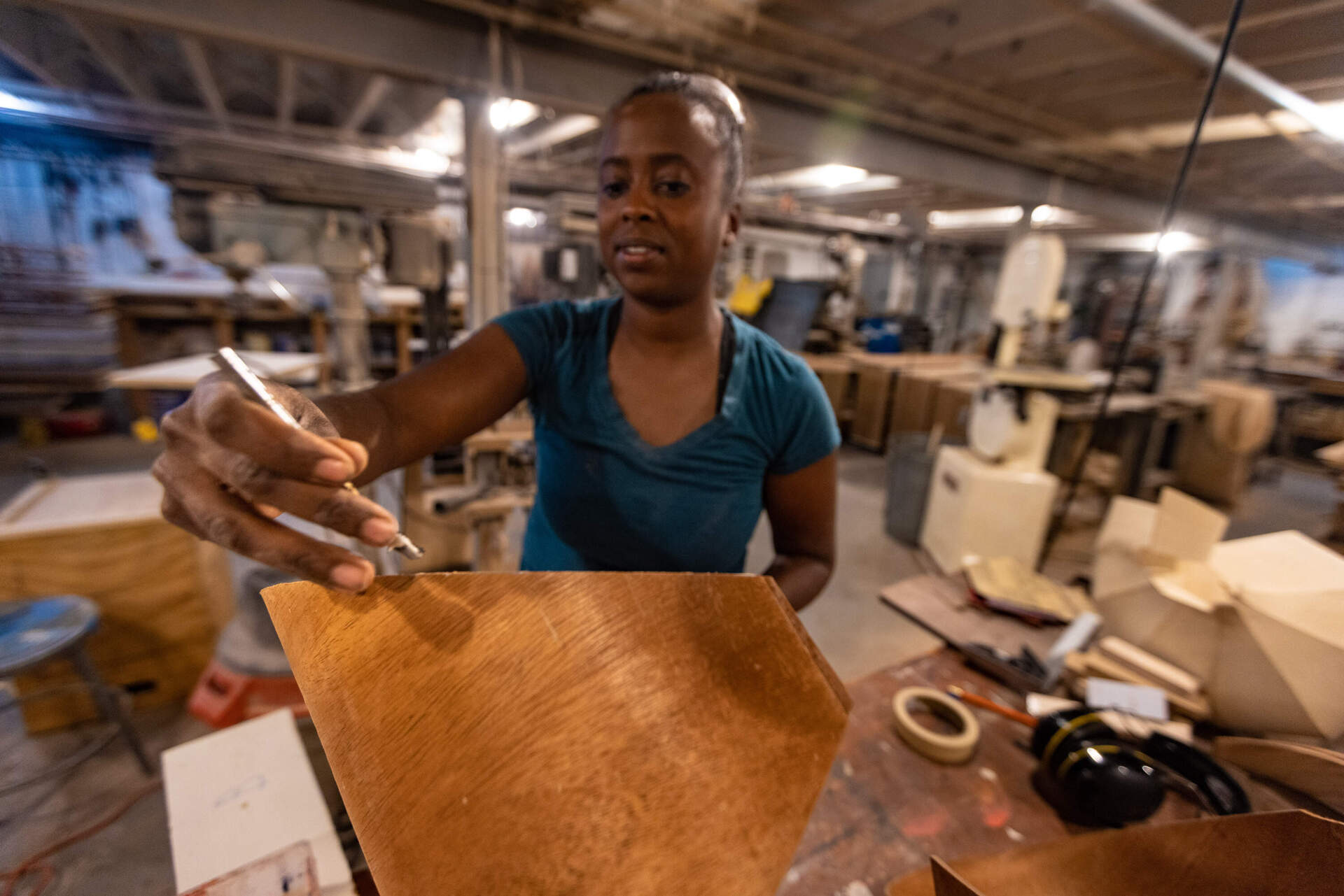 Alison Croney Moses applies wood glue to the edge of one veneer shell to attach it to another. (Jesse Costa/WBUR)