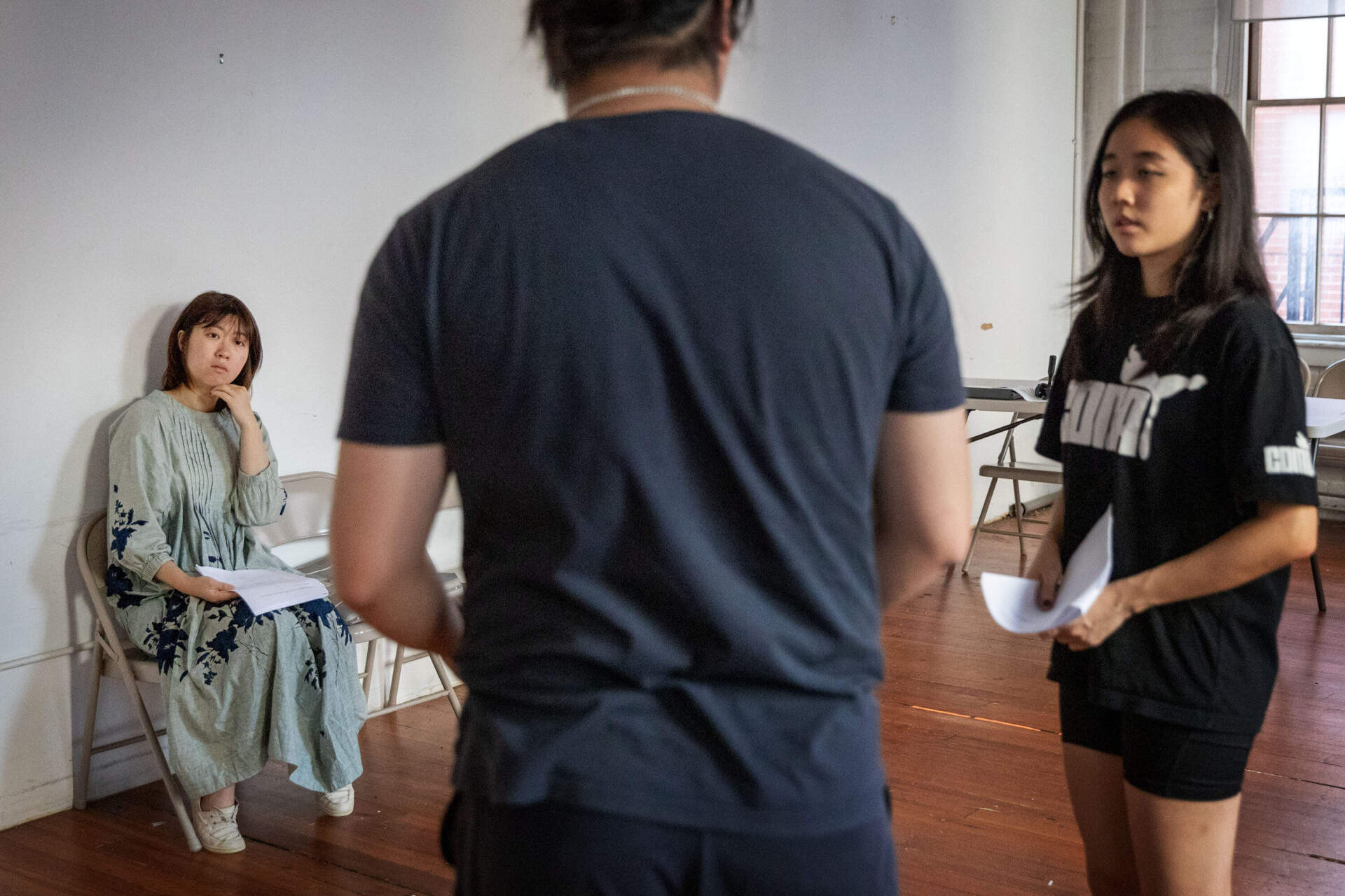 Theater producer and director Alison Qu watches actors in rehearsal at a Boston studio. (Robin Lubbock/WBUR)