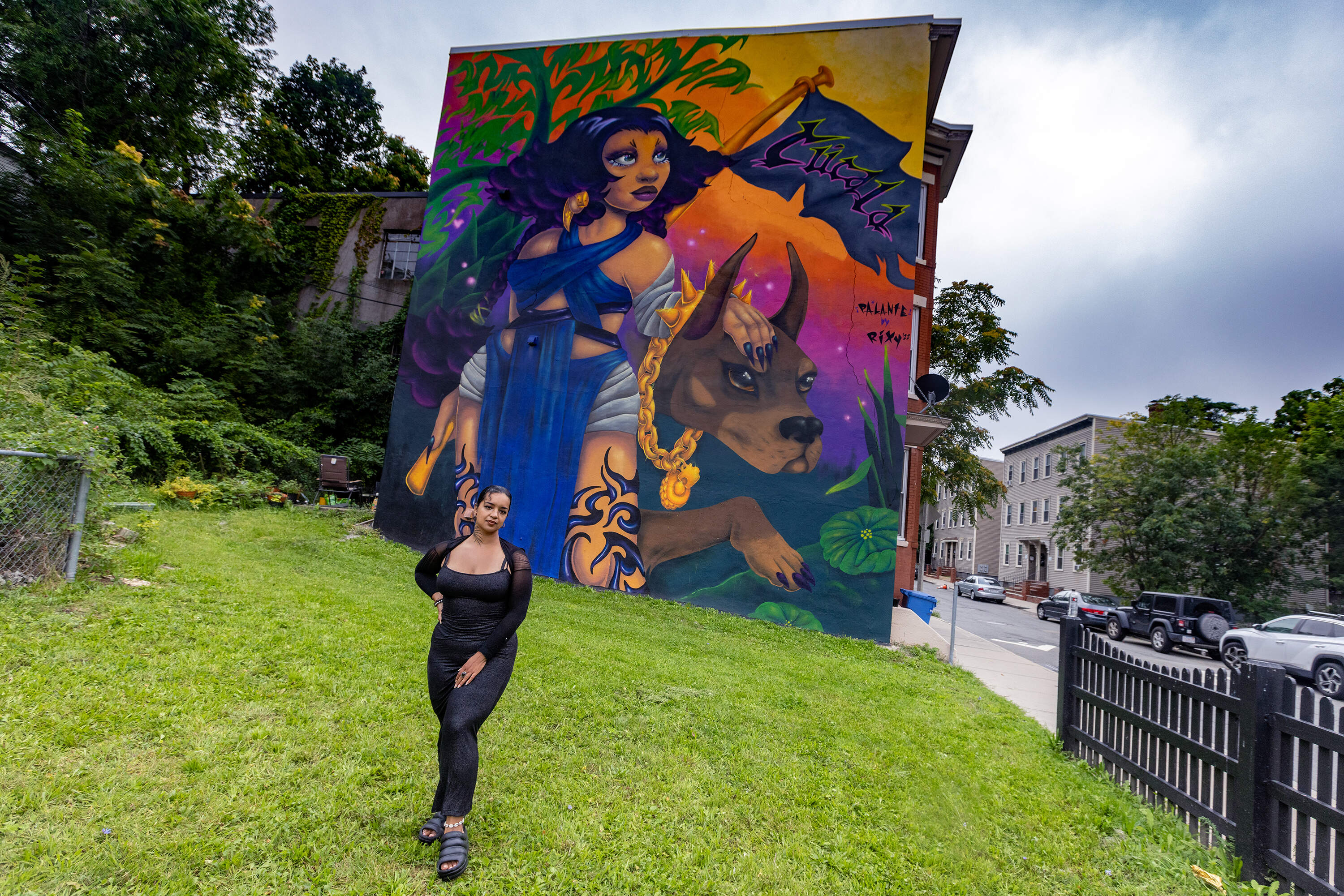 Artist and muralist Rixy stands in front of her work "Pa*Lante" in Roxbury. (Jesse Costa/WBUR)
