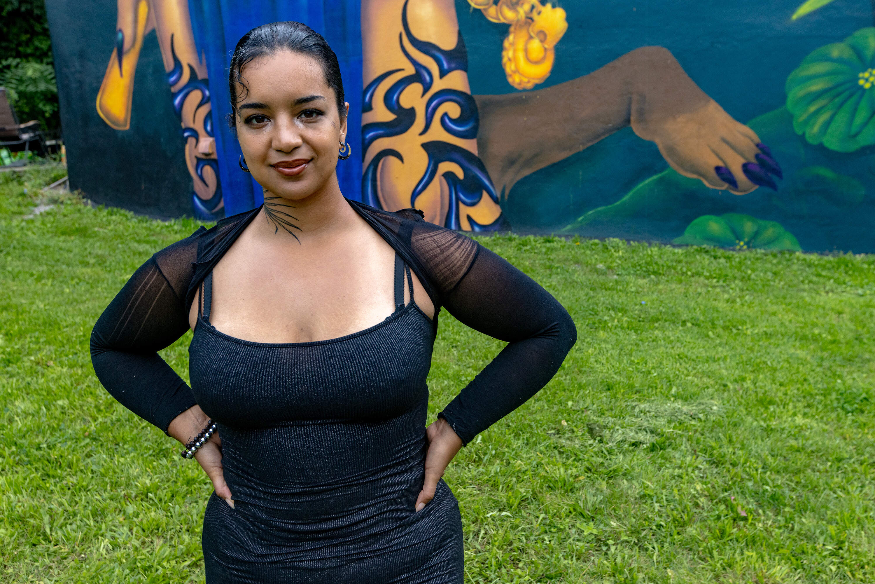 Artist and muralist Rixy stands in front of her work "Pa*Lante" in Roxbury. (Jesse Costa/WBUR)