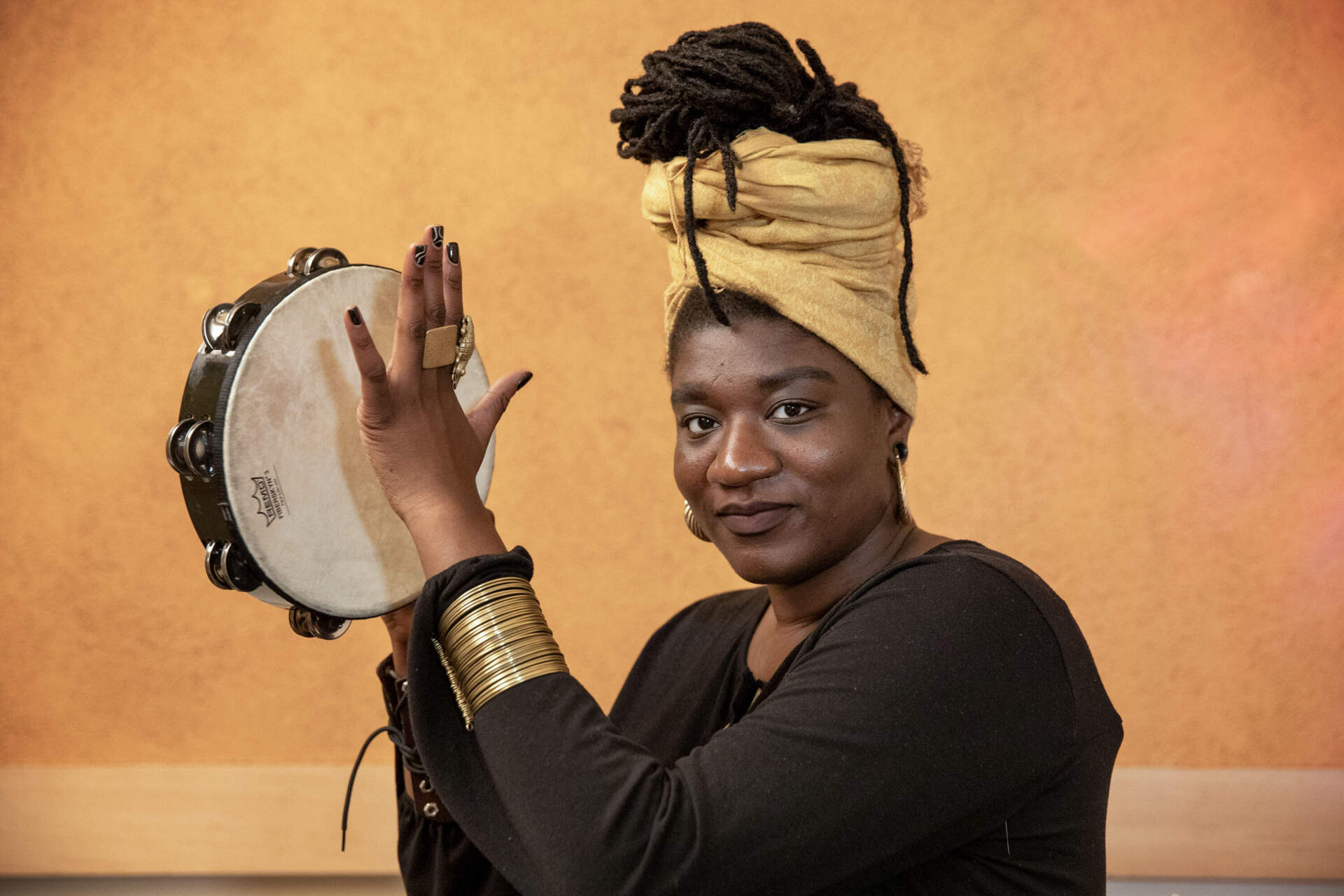 Poet and performance artist Dzidzor plays a tambourine in a Boston studio. (Robin Lubbock/WBUR)