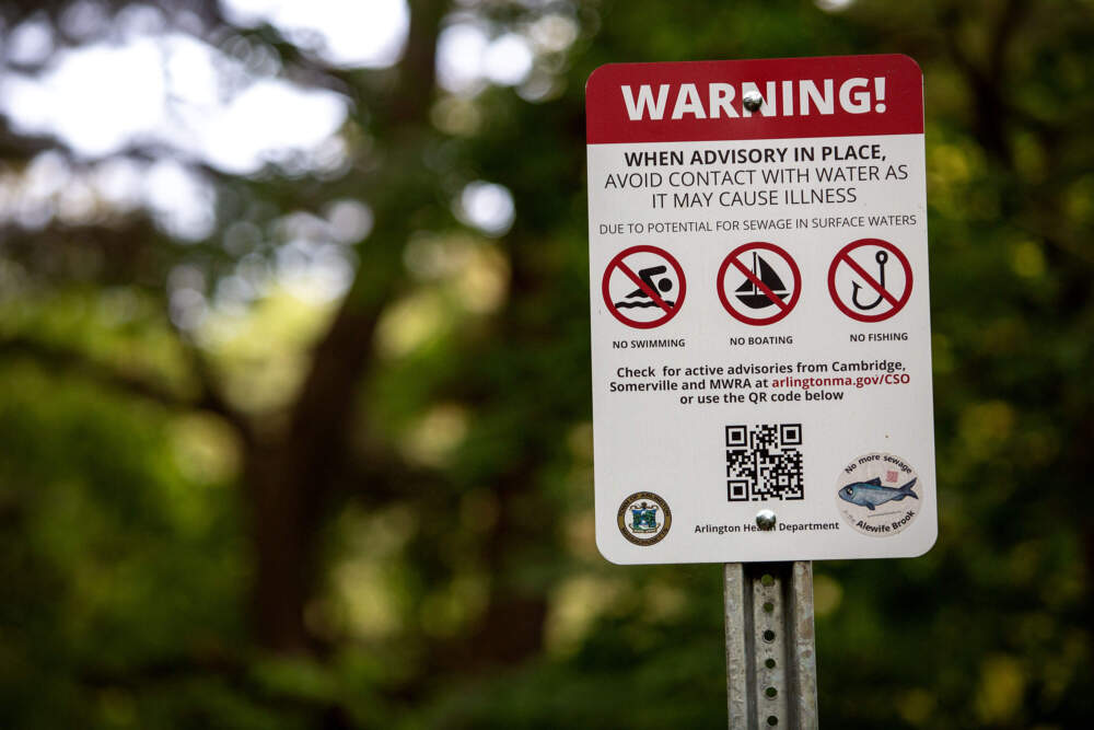 A sign warns people on the Alewife Greenway to stay out of Alewife Brook after a combined sewer overflow event (Robin Lubbock/WBUR)