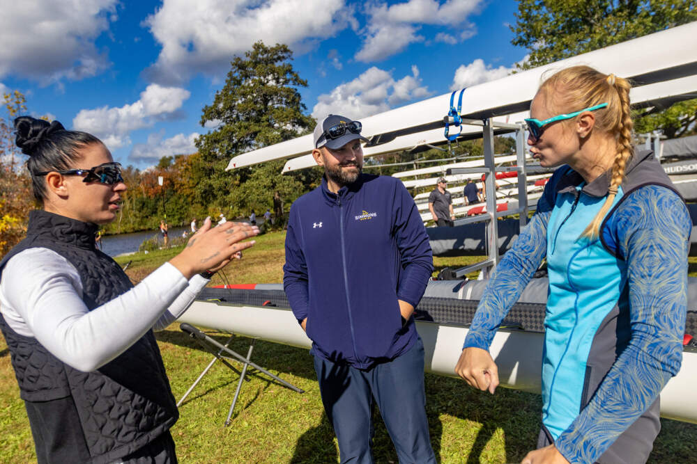 Simmons University head crew coach Andrii Ivanchuk has a fun moment with Ukrainian rowers Yevheniia Dovhodko and Anastasiia Kozhenkova before the Head of the Charles. (Jesse Costa/WBUR)