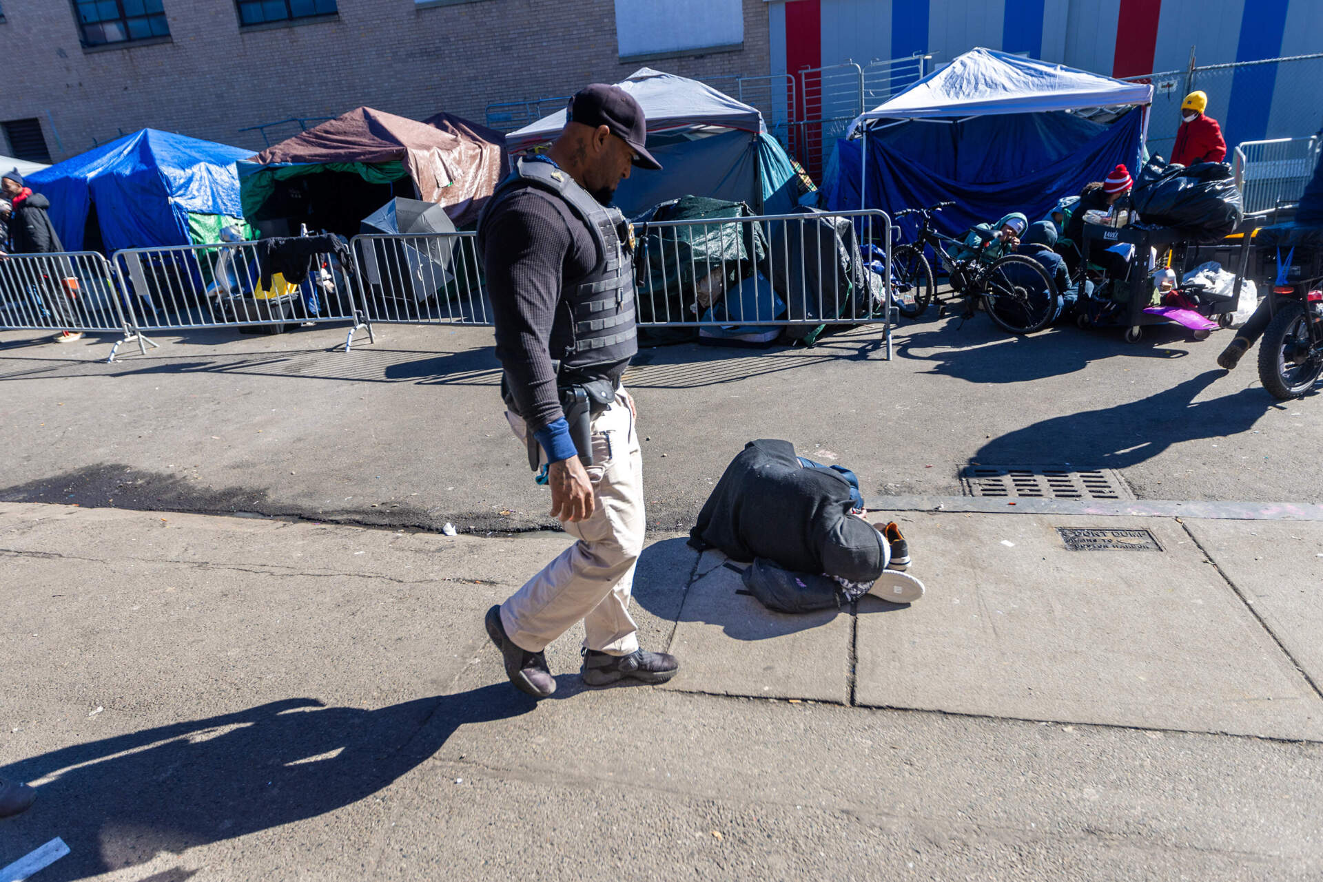Security guard Victor Arias looks at a person passed out on the sidewalk of Atkinson Street while patrolling the area. (Jesse Costa/WBUR)