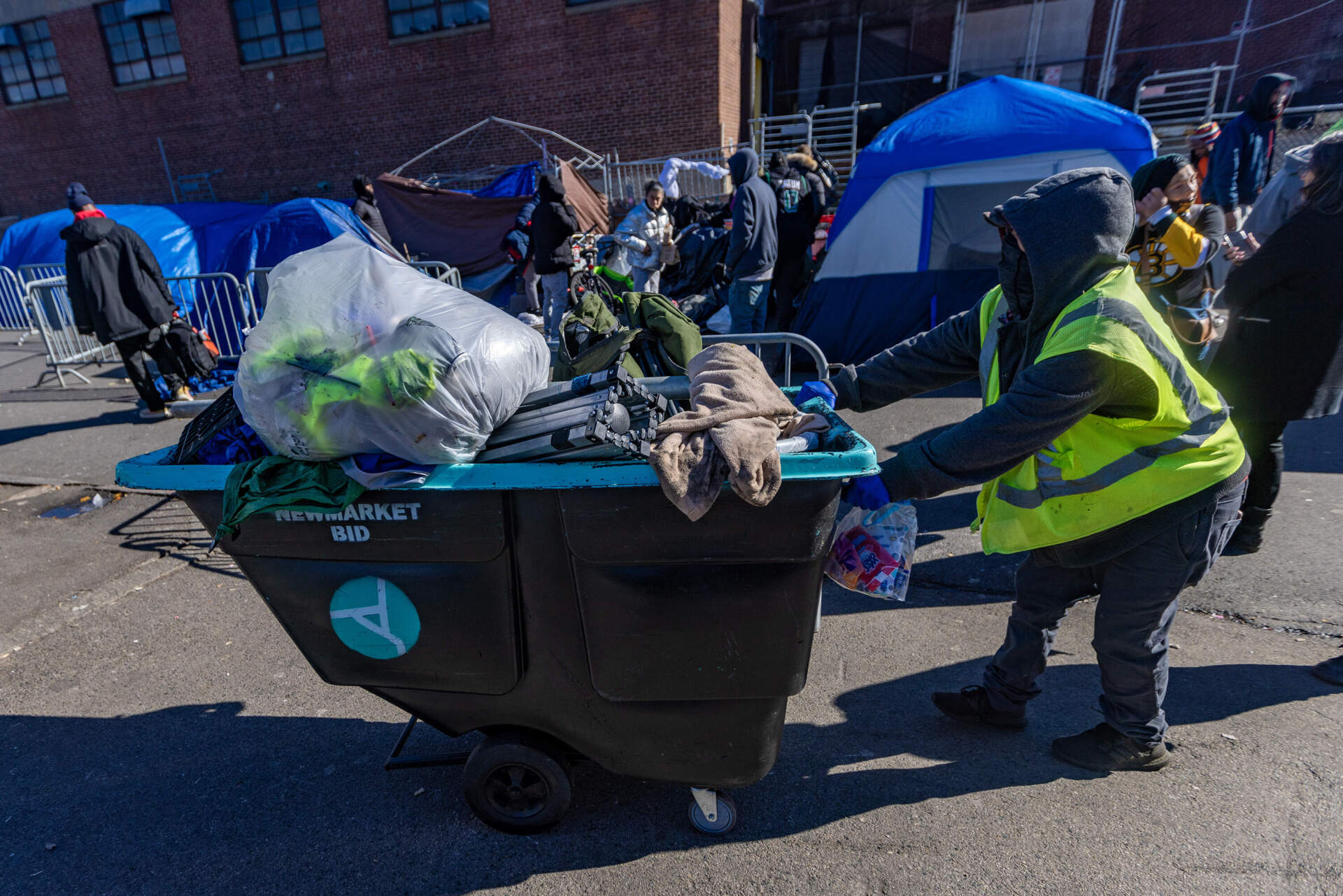A volunteer with the Newmarket Business Improvement District wheels a cart full of the belongings of someone who lived in a tent on Atkinson Street. The itms will be sent to the shelter where that person will be staying. (Jesse Costa/WBUR)