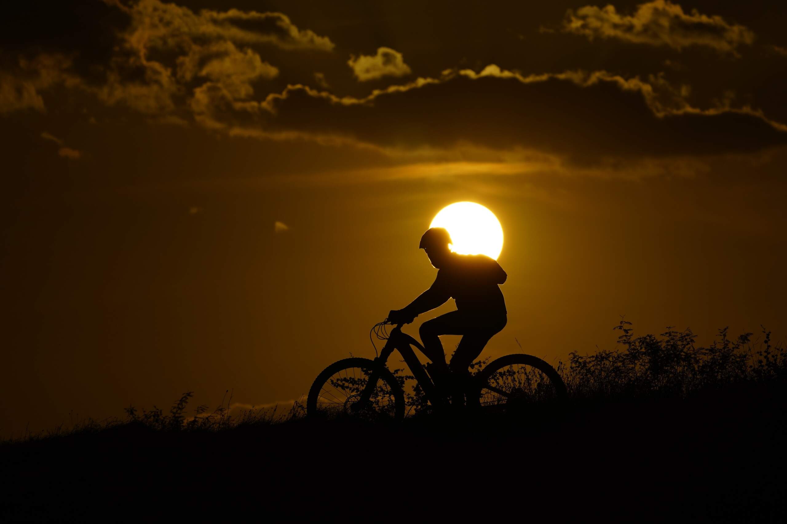 A cyclist tops a hill on a hot day at sunset in San Antonio. (Eric Gay/AP)