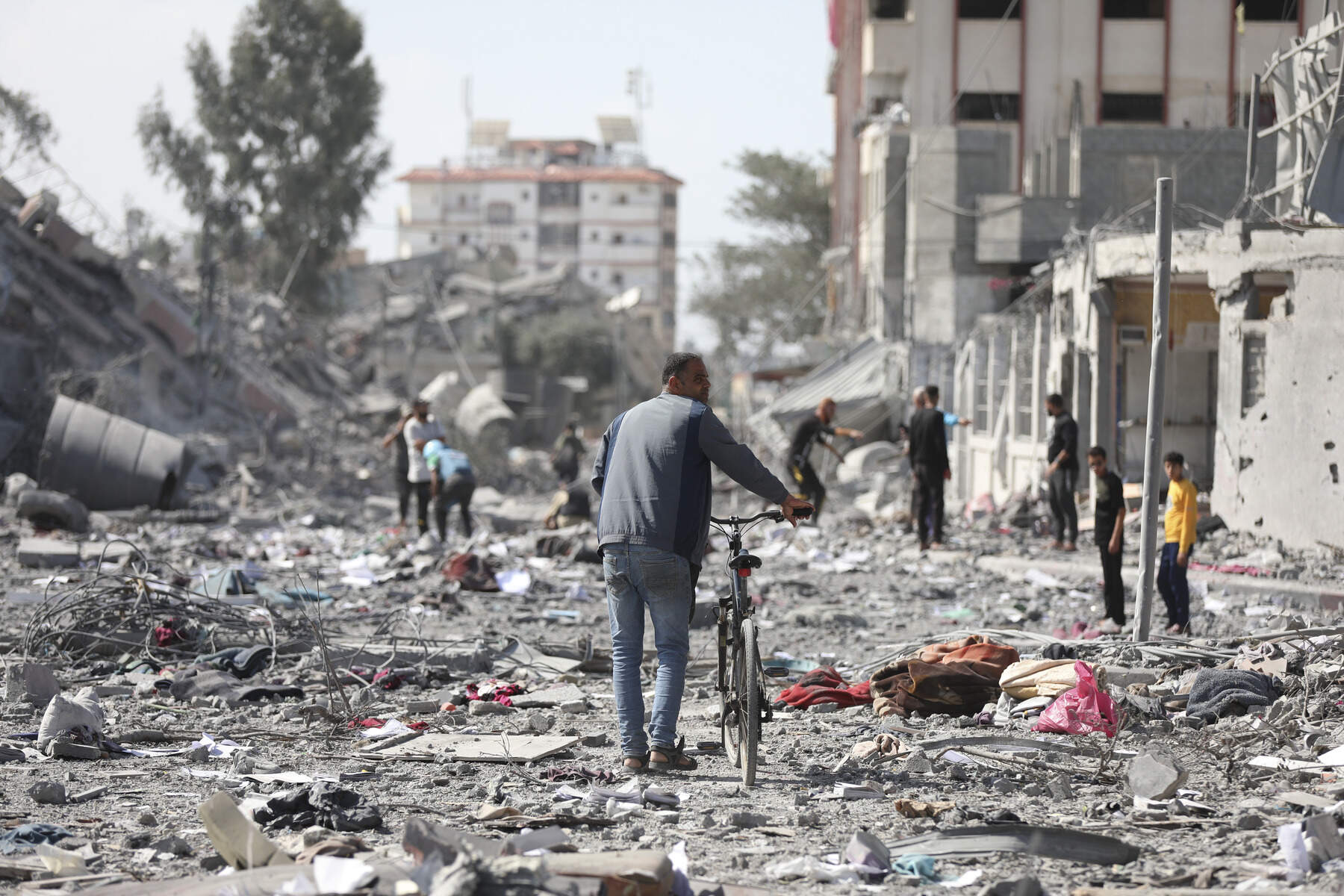 Palestinians walk by the buildings destroyed in the Israeli bombardment on al-Zahra, on the outskirts of Gaza City. (Ali Mahmoud/AP)
