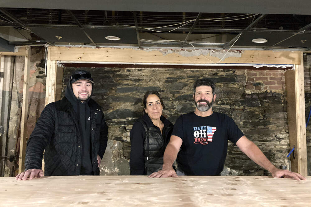 Jake Baraw, from left, Lisa Del Tufo and David Del Tufo stand inside their partially rebuilt bar Eight Oh Brew in Ludlow, Vt., Oct. 19, 2023, three months after severe flooding in the ski town. They hope to reopen by mid-December of 2023. (Lisa Rathke/AP)