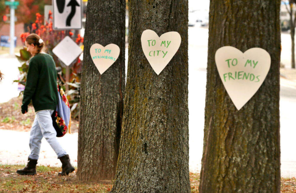 Artist Miia Zellner walks away after nailing hearts she made to trees on Main Street in Lewiston, ME, the day after a mass shooting took place in the city. (John Tlumacki/The Boston Globe via Getty Images)
