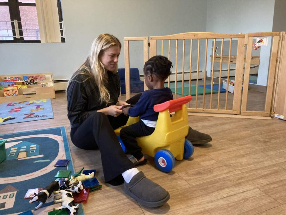 Ruby Gottlieb, a volunteer with Horizons for Homeless Children, plays with a child in a shelter playroom. (Gabrielle Emanuel/WBUR)