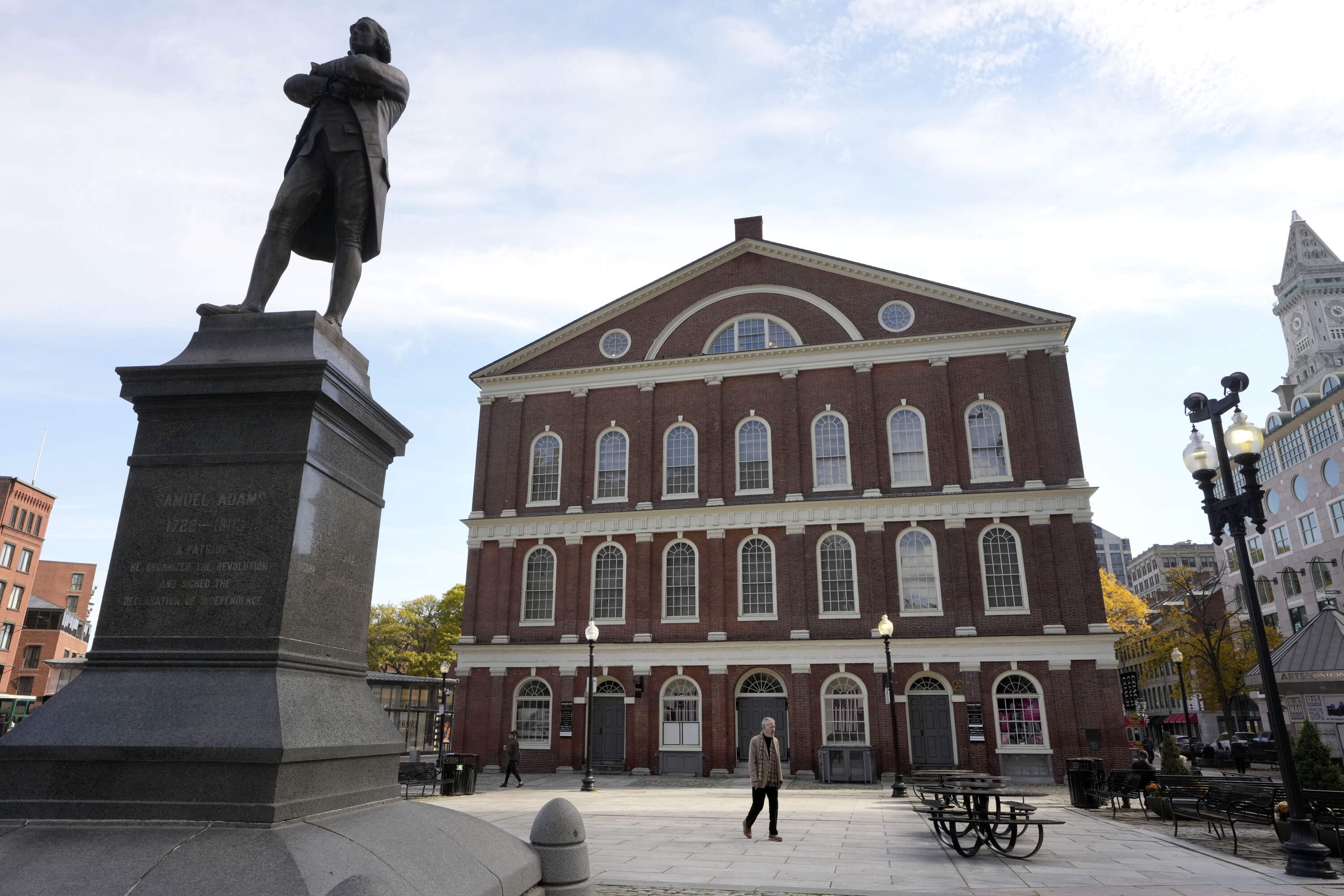 A statue of Samuel Adams, left, stands near Faneuil Hall. Boston City Council members voted Wednesday in favor of holding a hearing on the renaming of the popular tourist site. (Steven Senne/AP)