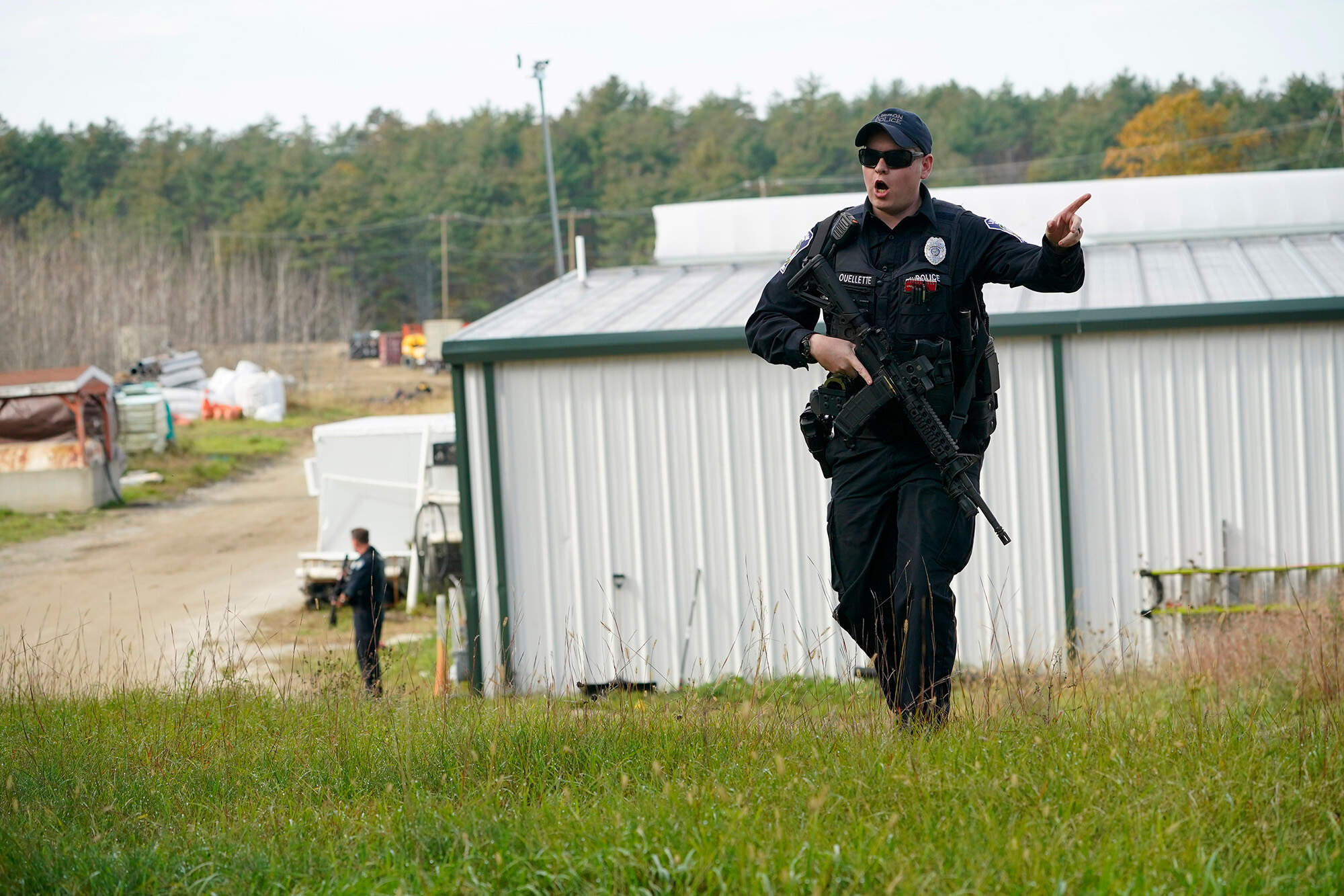 A police officer gives an order on Friday during a search at a farm in Lisbon, Maine, for the suspect in this week's deadly mass shootings. (Robert F. Bukaty/AP)