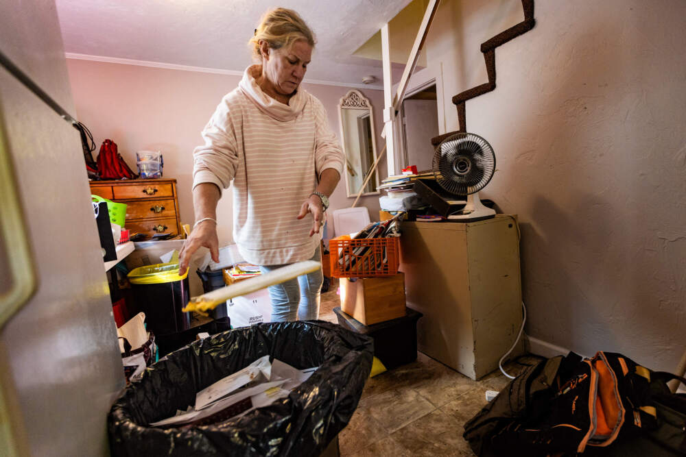 Deb Libby tosses some personal paperwork she does not want to keep into a trash barrel as she is evicted from her apartment in Worcester. (Jesse Costa/WBUR)