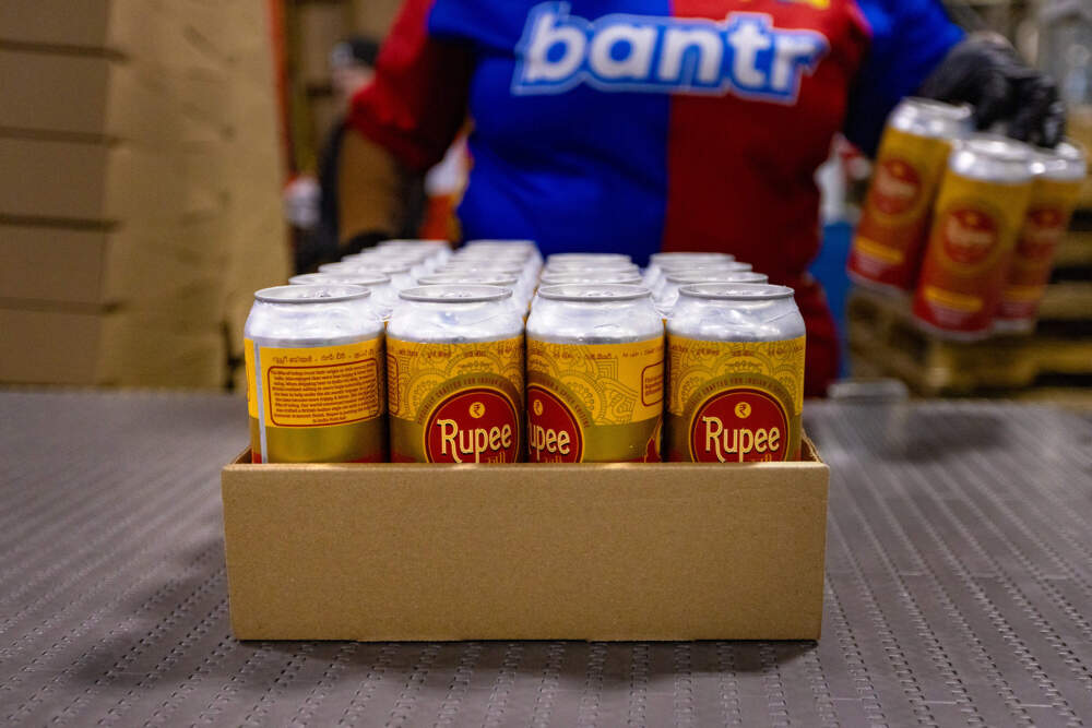 The new Rupee IPA cans being boxed up in cases after going through the canning line at Dorchester Brewing in time for the Diwali celebration. (Jesse Costa/WBUR)