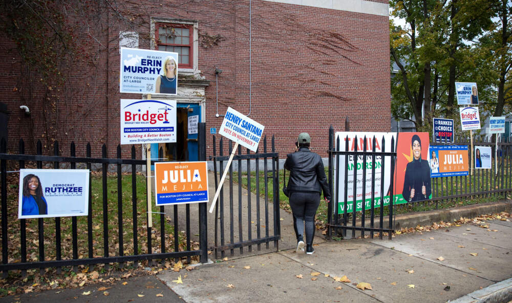 A voter walks past campaign banners to vote at the Higginson-Lewis School in Roxbury. (Robin Lubbock/WBUR)