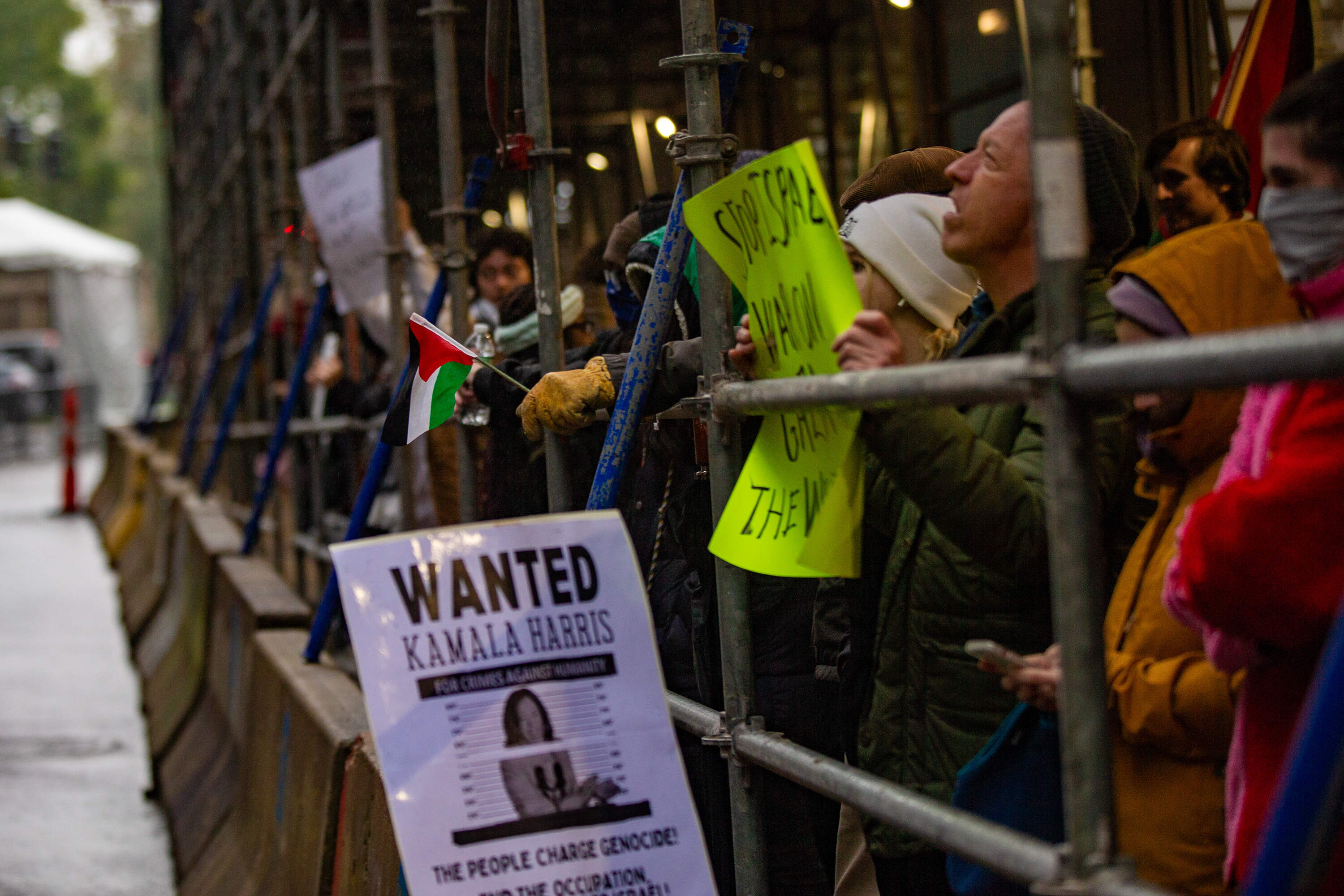 Protestors gather under the scaffolding across the street from the Ritz Carlton during VP Harris visit. (Jesse Costa/WBUR)