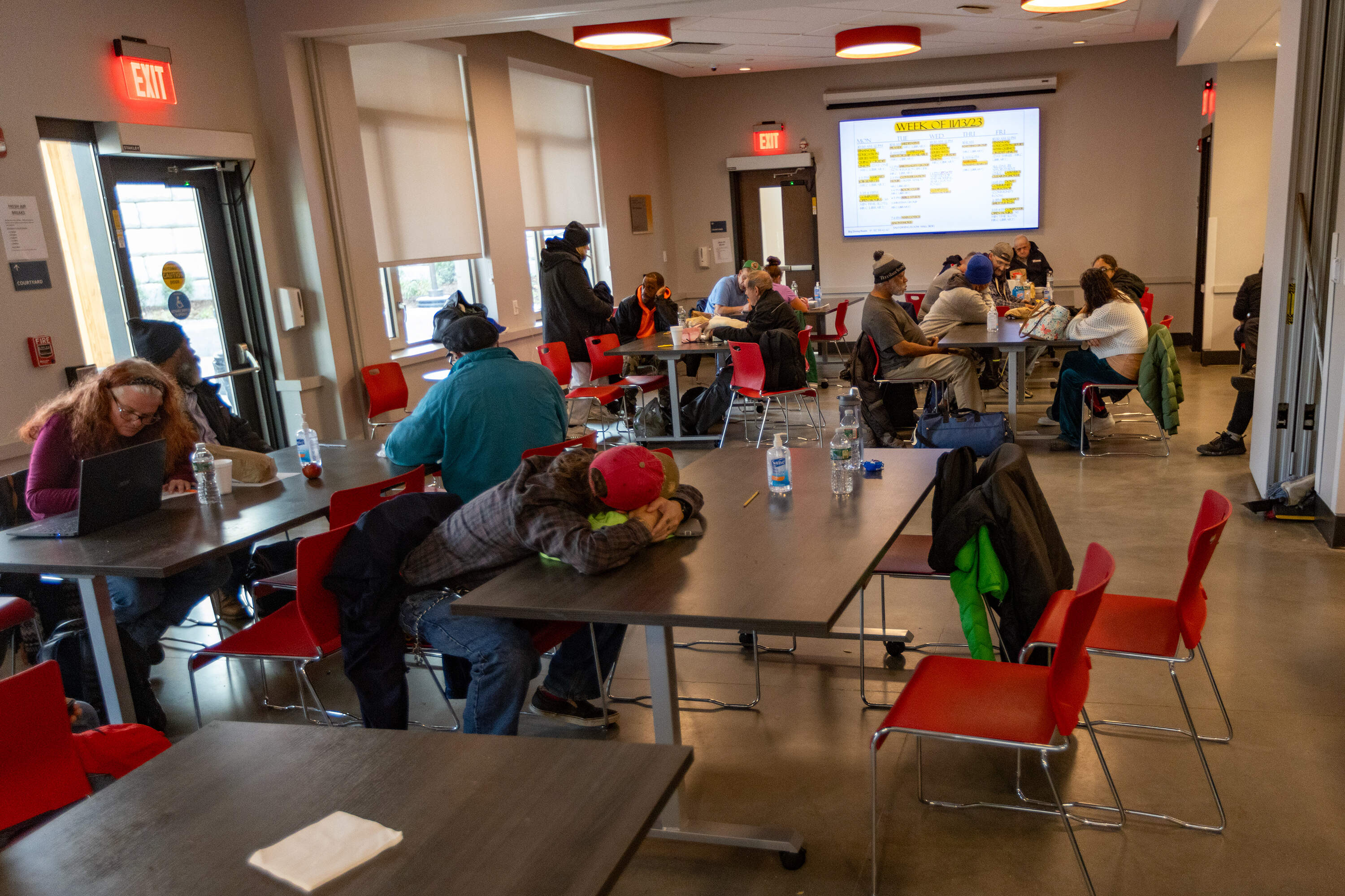 People use the cafeteria at Father Bill's & MainSpring's new Yawkey Housing Resource Center to stay warm during the day, and 15 or more adults have been sleeping in the room on mats at night because the facility's shelter beds are full. (Jesse Costa/WBUR)