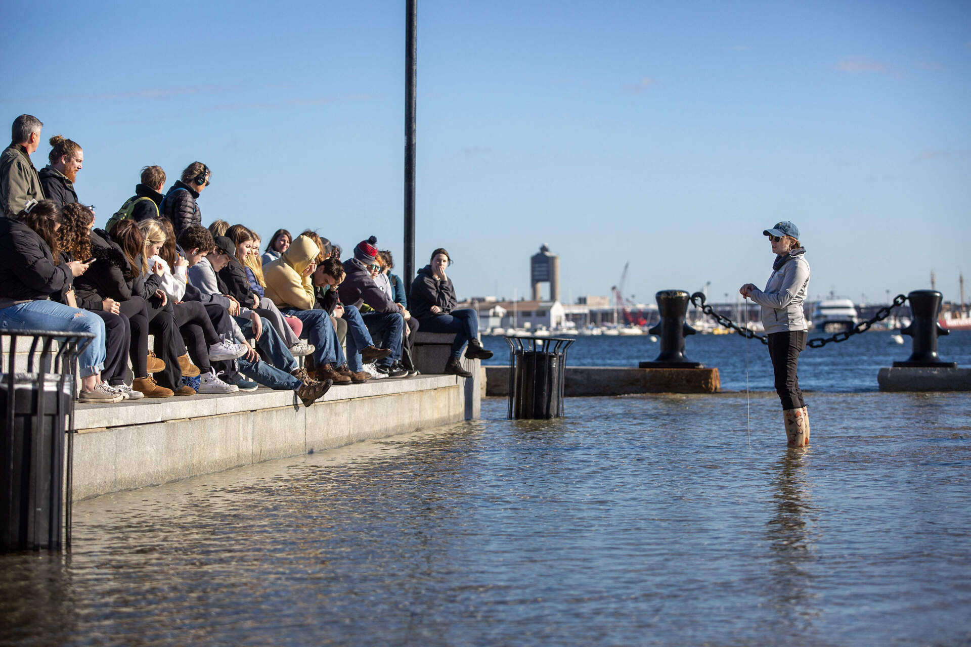 Rebecca Shoer, education and engagement program manager at Stone Living Lab, talks to a group of students during a king tide at Long Wharf. (Robin Lubbock/WBUR)