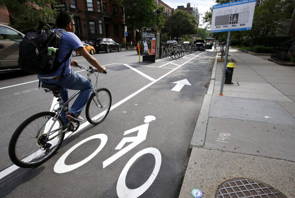 In this 2016 photo, a cyclist enters a bike lane routed between parked cars and the sidewalk in Boston. (Steven Senne/AP)