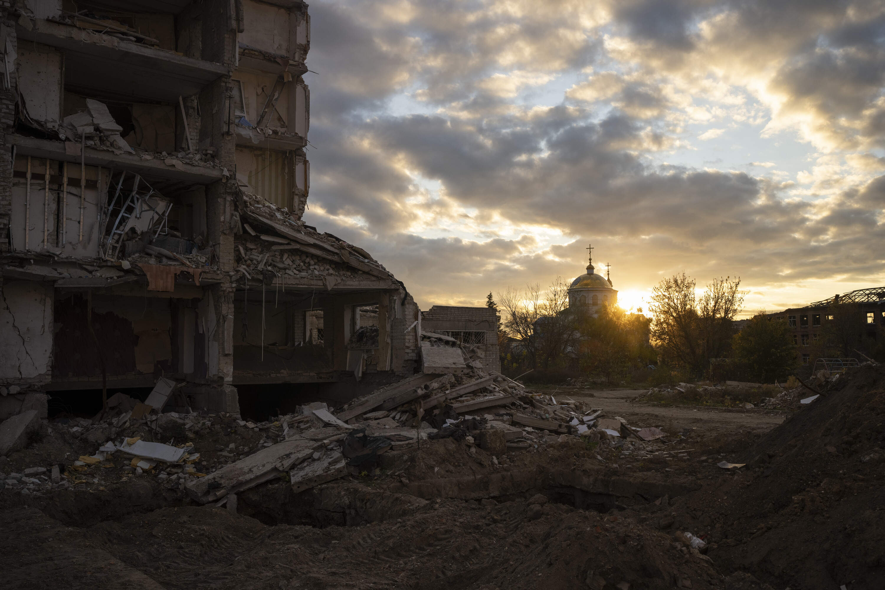 The sun sets over a destroyed building in Izyum, Ukraine. (Bram Janssen/AP)