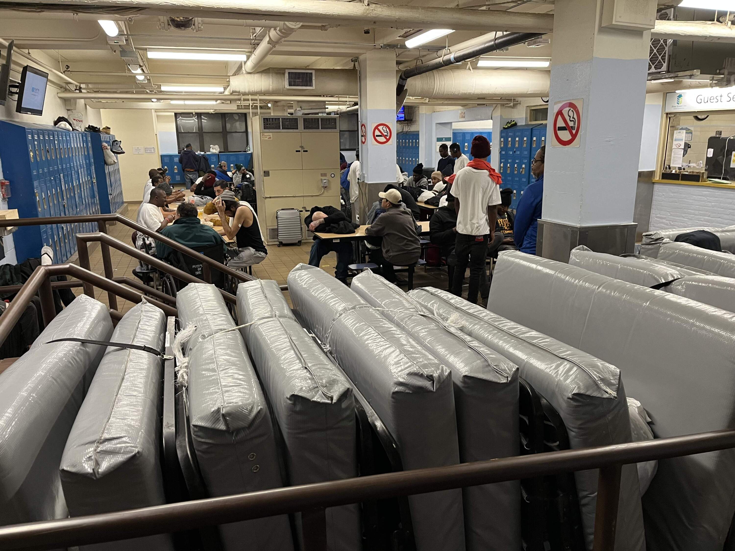 Men gather in a common room at Pine Street Inn in Boston while they await beds for the night. This room and the shelter dining room are being used as overflow shelter spaces, where men sleep on rollaway cots, mats and chairs. (Lynn Jolicoeur/WBUR)
