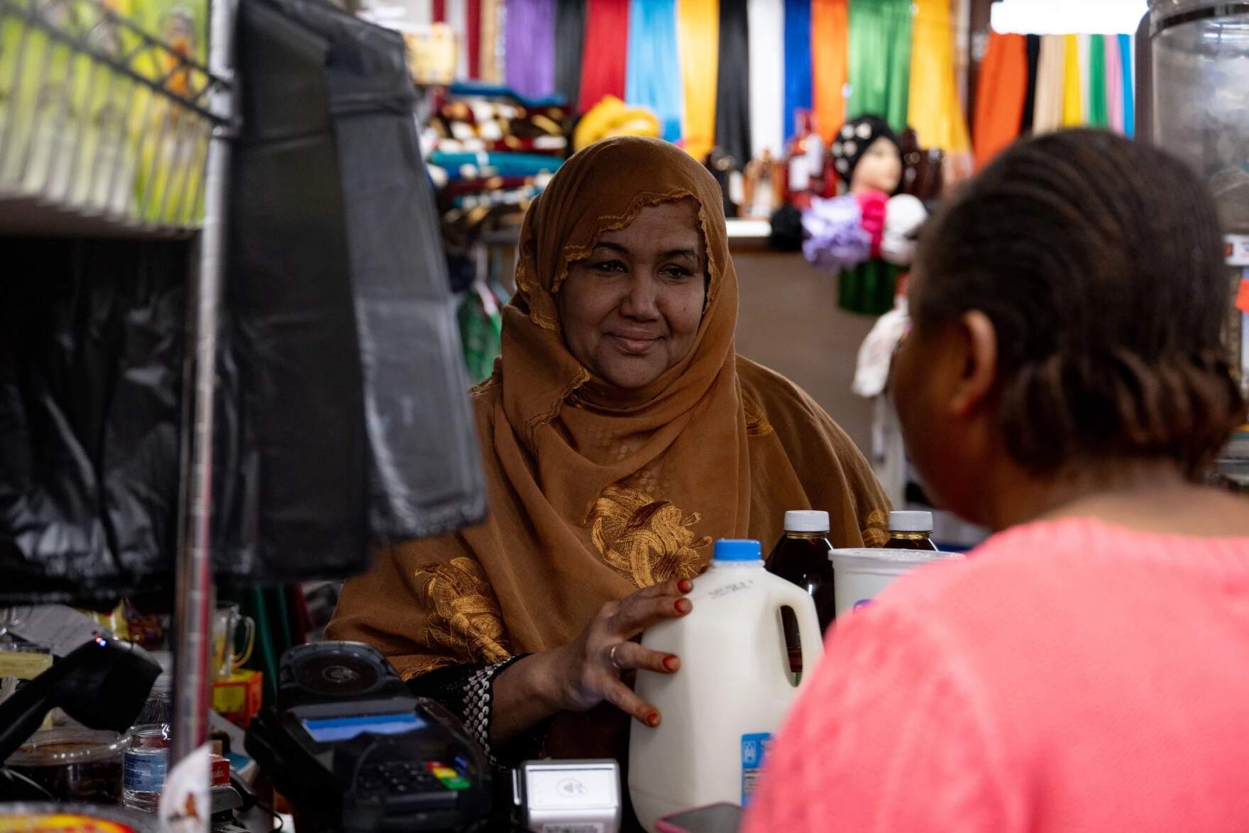 Shukri Abasheikh, owner of Mogadishu Store, helps customer Gracia Mbula with a purchase in her store in Lewiston, Maine, on Monday, Oct. 30, 2023. (Raquel C. Zaldívar/New England News Collaborative)
