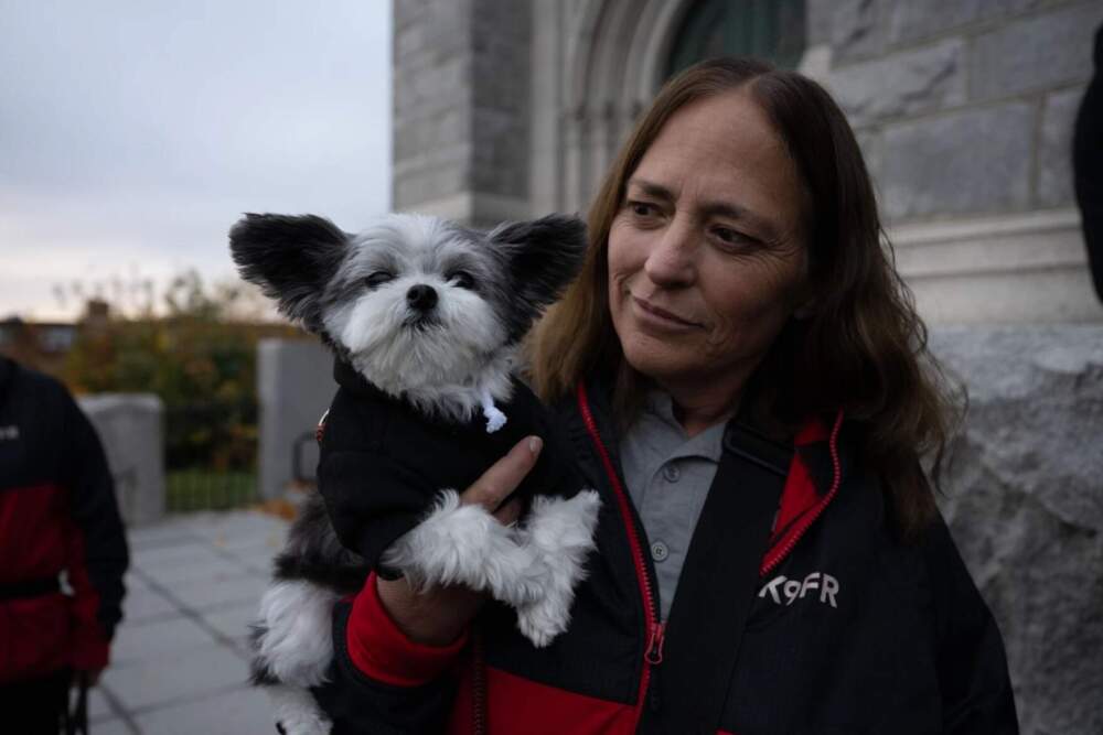 Jen Adams looks at Gadget the dog, who was providing therapy dog services at the OneLewiston Community Vigil in the Basilica of Saints Peter and Paul in Lewiston, Maine, on Sunday, Oct. 29, 2023. (Raquel C. Zaldívar/New England News Collaborative)