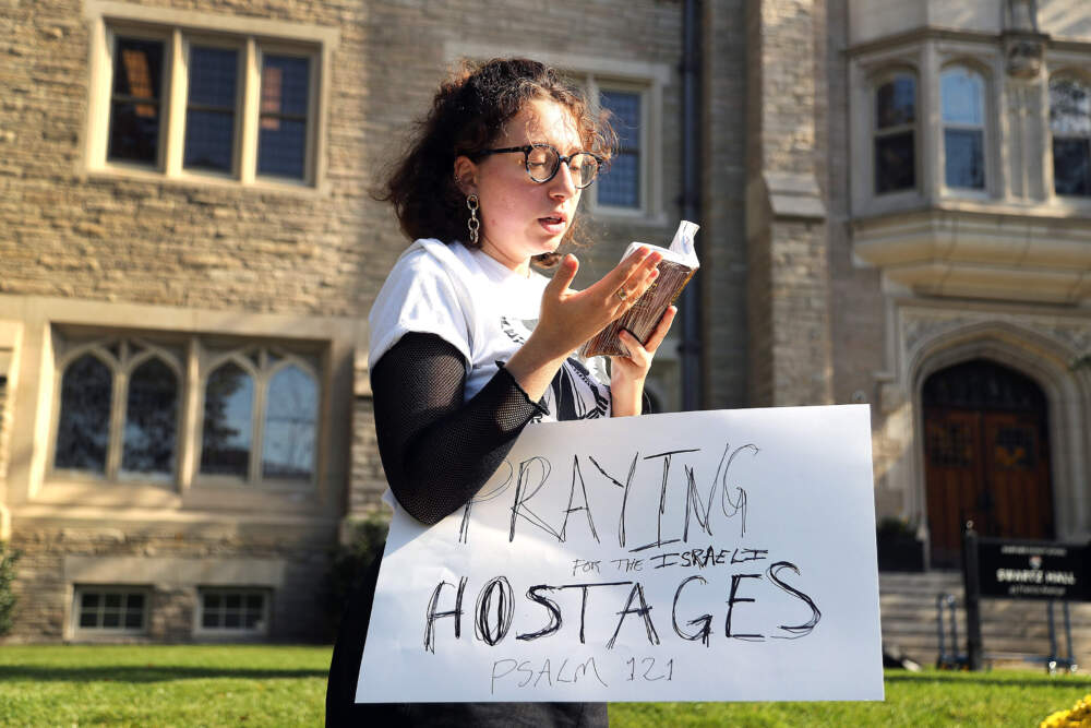 On Oct. 25, a woman prays aloud for the Israeli hostages as she stands away from Harvard students and faculty rallying outside the Harvard Divinity School in solidarity with Palestinians. (John Tlumacki/The Boston Globe via Getty Images)