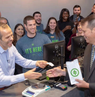 Then-Mayor David Narkiewicz, far right, moves to shake hands with a NETA employee as he purchases the first legally sold piece of recreational cannabis in Northampton. (Courtesy Kelly Beaudoin of NETA)