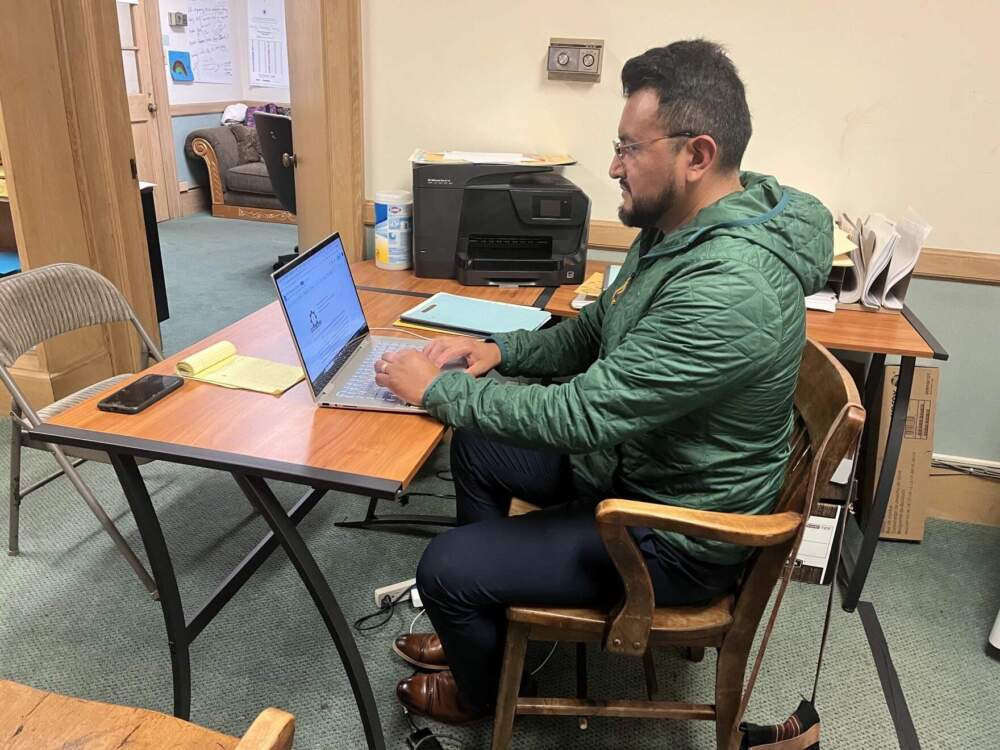 Leninn Torres, an organizer at the Pioneer Valley Workers' Center, translates birth certificates in English for undocumented immigrants applying for their Massachusetts driver's license. (Nirvani Williams/NEPM)