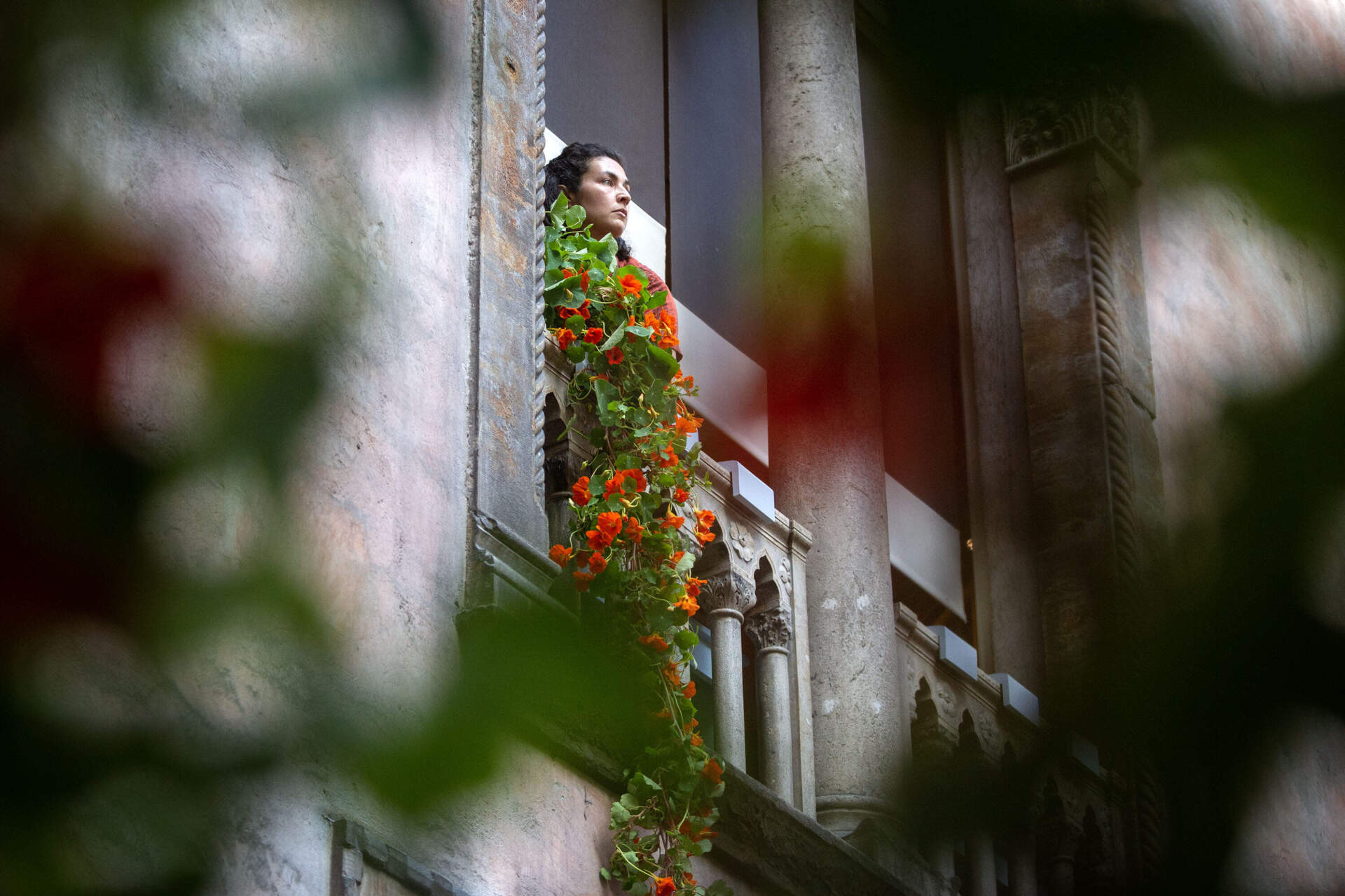 Horticulture Director Erika Rumbley carefully lowers nasturtiums out of a window into the courtyard of the Isabella Stewart Gardner Museum. (Robin Lubbock/WBUR)