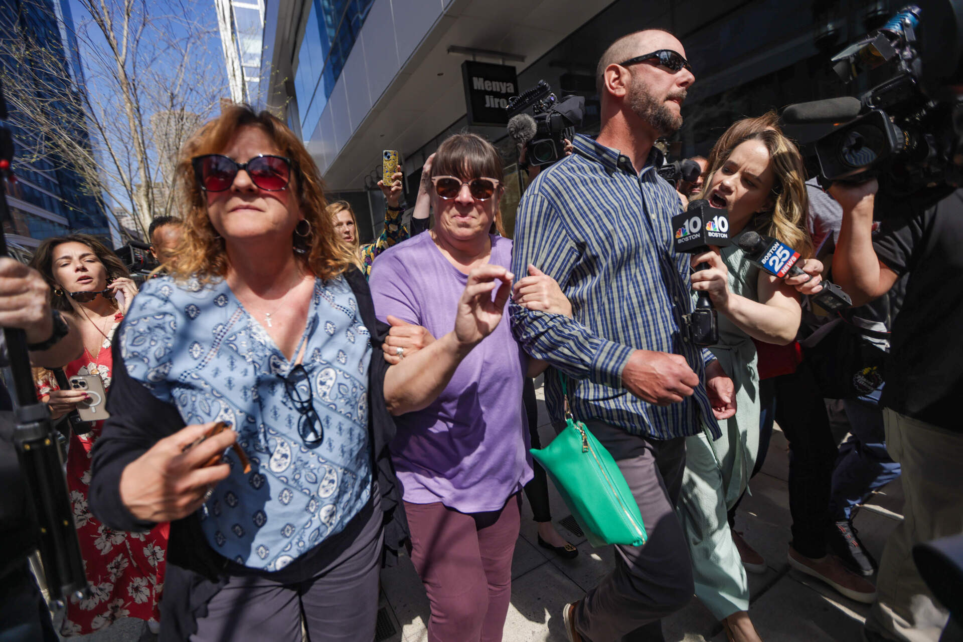 News media surround family members of Jack Teixeira after his arraignment as they leave Moakley Federal Courthouse in Boston. (Jesse Costa/WBUR)