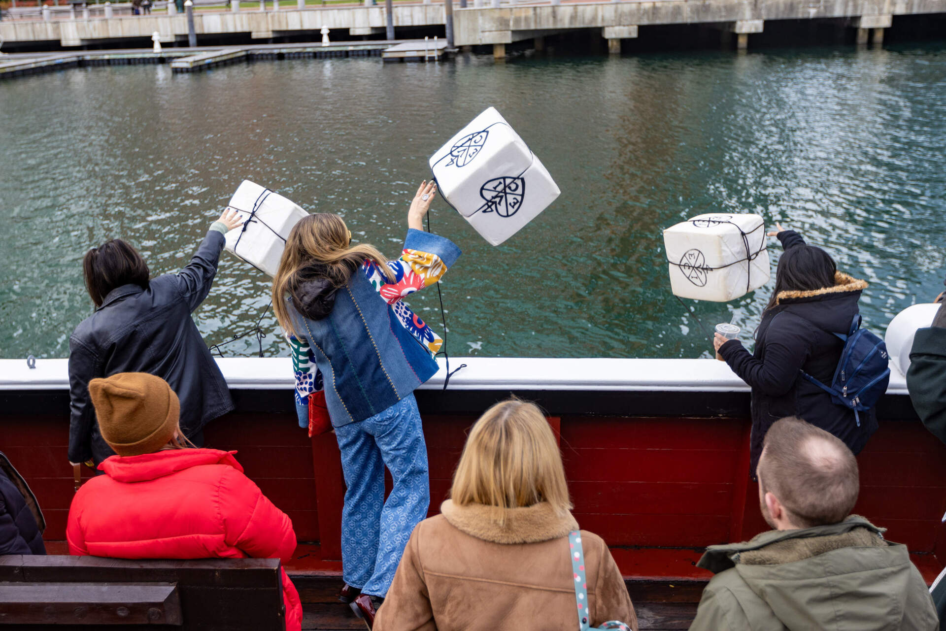 Museum goers toss crates with the emblem of the East India Company overboard into the Fort Point Channel from the brig Beaver during a visit to the Boston Tea Party Museum. (Jesse Costa/WBUR)