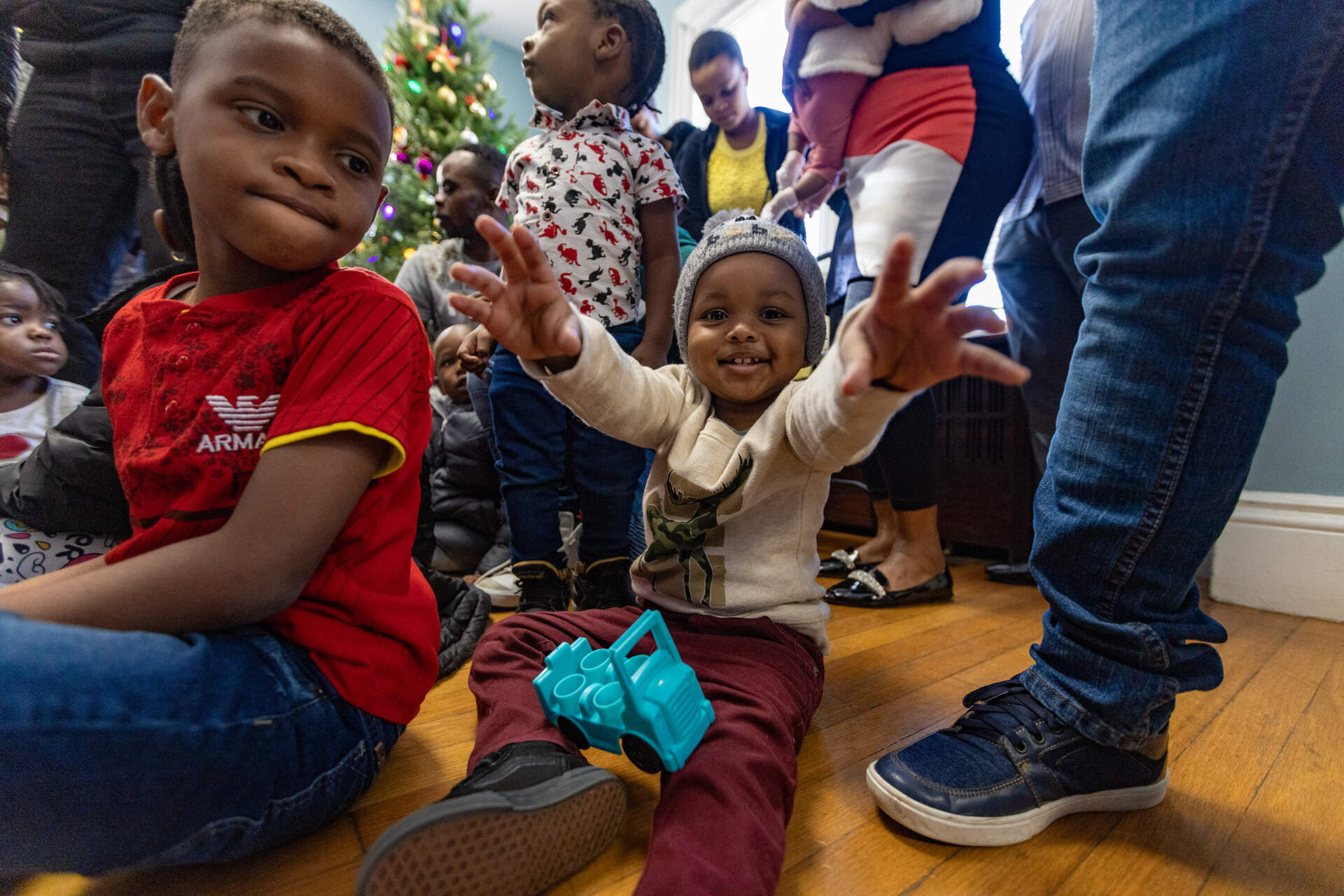 Migrant children from Haiti congregate around a Christmas tree in the community room at the Bethel AME Church rectory in Jamaica Plain. (Jesse Costa/WBUR)