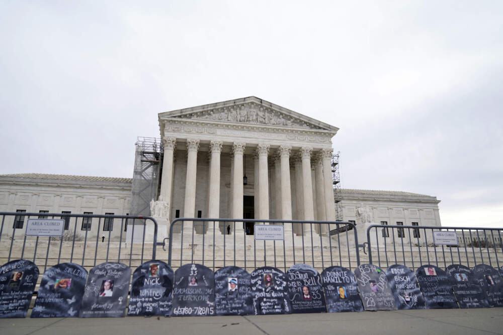 Signs in the shape of grave headstones with information on people who died from using OxyContin line a security fence outside the Supreme Court. (Stephanie Scarbrough/AP)