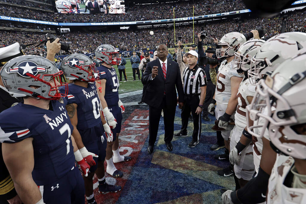 Defense Secretary Lloyd Austin flips the coin before the first half of an NCAA college football game between Army and Navy in 2021. (Adam Hunger/AP)