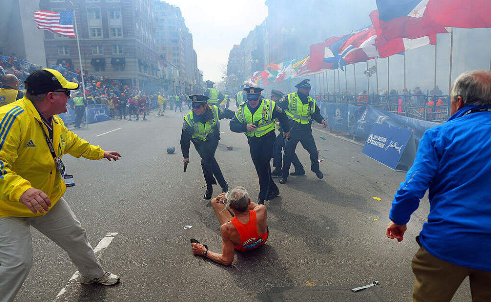 Police officers with their guns drawn hear the second explosion down the street on April 15, 2013. The first explosion knocked down 78-year-old US marathon runner Bill Iffrig at the finish line of the 117th Boston Marathon. (John Tlumacki/The Boston Globe via Getty Images)