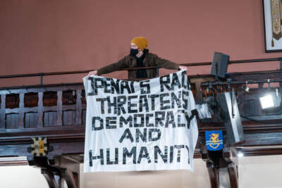A protestor holds up a banner during Sam Altman's visit to The Cambridge Union to receive the Professor Hawking Fellowship on behalf of OpenAI on November 01, 2023 in Cambridge, England. (Nordin Catic/Getty Images)